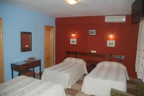 two beds in a room with red walls at Hostal Residencia Castilla in Cuenca