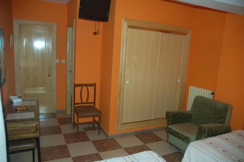 a room with a bed and a chair and a television at Hostal Residencia Castilla in Cuenca