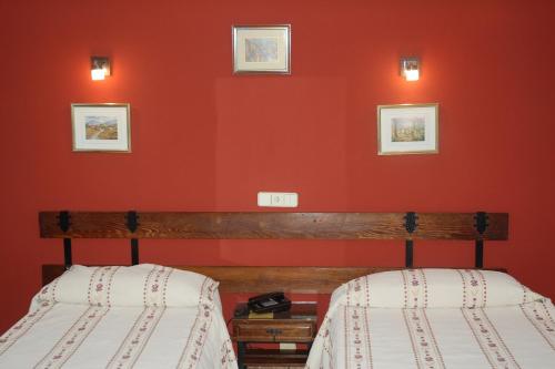 two beds in a room with red walls at Hostal Residencia Castilla in Cuenca