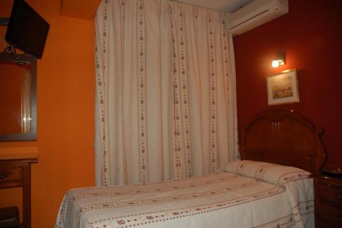 a small bedroom with a bed and a curtain at Hostal Residencia Castilla in Cuenca