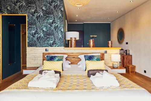 a living room with a large bed with pillows at Domaine de Chalvêches Hôtel SPA 4* in Faugères