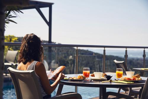 a woman sitting at a table with a plate of food at Domaine de Chalvêches Hôtel SPA 4* in Faugères