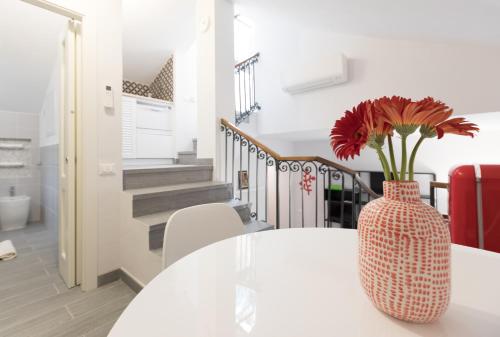 een vaas met rode bloemen op een witte tafel bij Quiet pied a terre with terrace in Borgo Pio in Rome