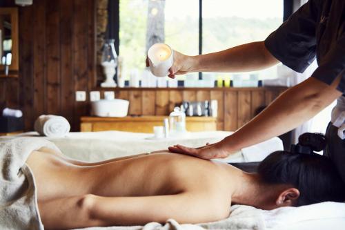 a woman laying on a bed getting a massage at Domaine de Chalvêches Hôtel SPA 4* in Faugères