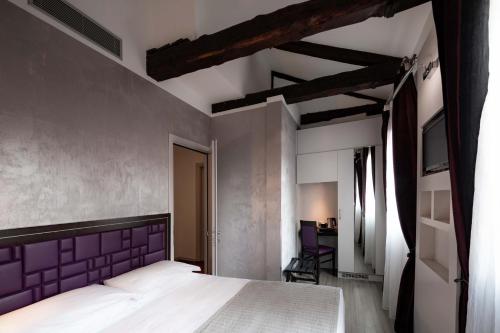 a bedroom with a large bed with a purple headboard at Hotel Paganelli in Venice