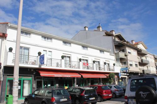 a large white building with cars parked in front of it at Residencial Tropicália AL in Praia da Barra