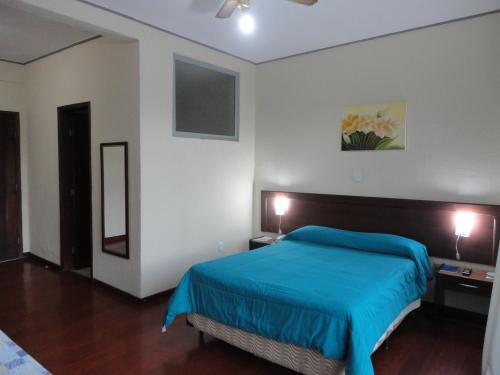 1 dormitorio con 1 cama azul en una habitación blanca en Jóia Hotel, en Poços de Caldas