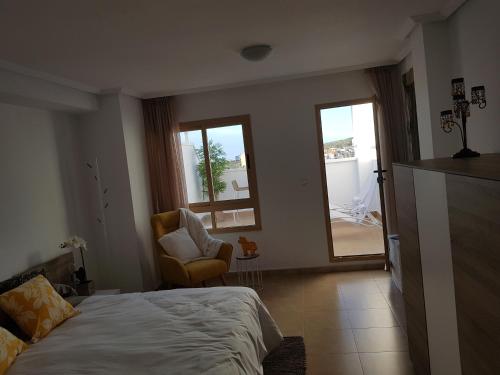 グアルダマル・デル・セグラにあるApartamento Mediterraneo Guardamarのベッドルーム1室(ベッド1台、椅子、窓付)