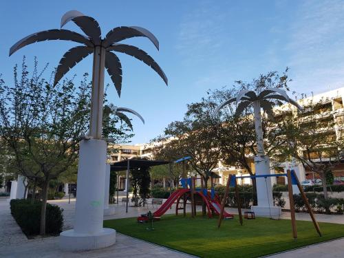 a playground with a slide in a park with palm trees at Apartamento Mediterraneo Guardamar in Guardamar del Segura