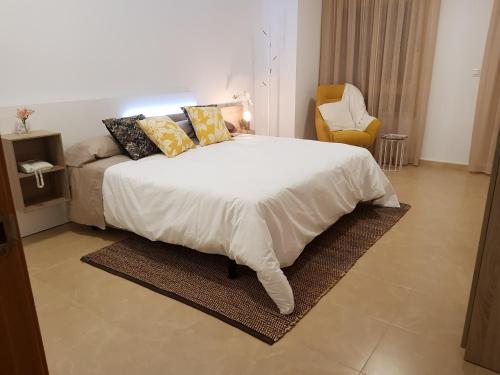 a bedroom with a white bed and a yellow chair at Apartamento Mediterraneo Guardamar in Guardamar del Segura