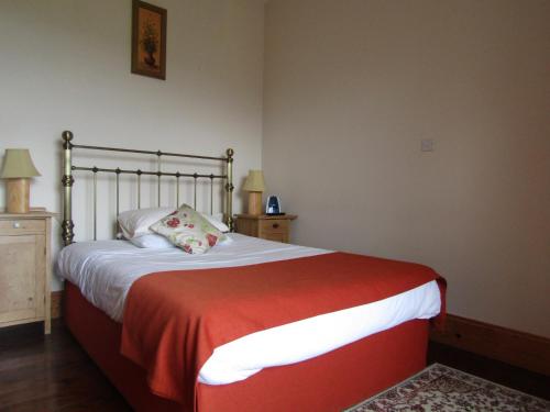 a bedroom with a bed with a red and white blanket at Berry Lodge Country House in Spanish Point
