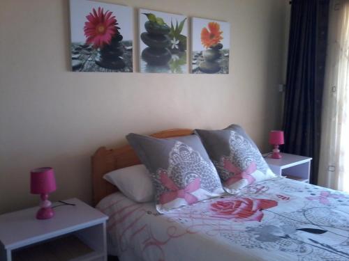 a bedroom with a bed with pink lamps and pictures on the wall at Chez Cozy's in Albion