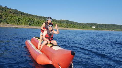 two people are riding on an orange raft in the water at 海灘戀情 Beach Love 近沙灘-國旅卡特約商店 陽台房 希臘地中海風格 in Eluan
