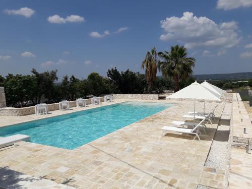 una piscina con tumbonas y sombrilla en Masseria La Gravina, en Palagianello