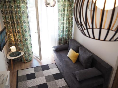 ein Wohnzimmer mit einem braunen Sofa und einem gelben Kissen in der Unterkunft Apartament Mrągowska - Żabi Staw in Mikołajki