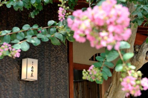 a bunch of pink flowers in front of a door at Yadoya Nishijinso in Kyoto