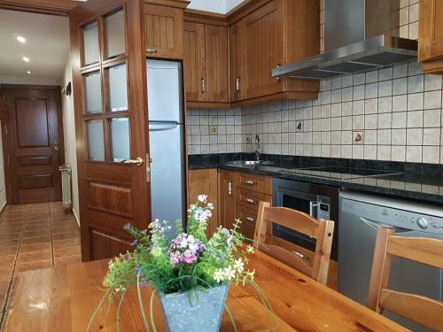 a kitchen with a wooden table and a refrigerator at Apartaments Cal Noi in Camprodon