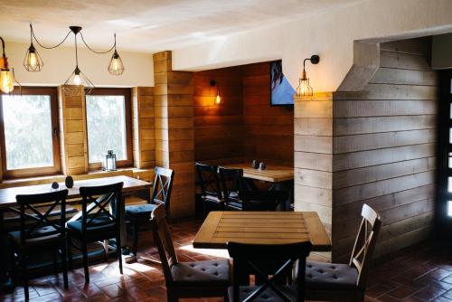 a restaurant with wooden walls and tables and chairs at Madarasi Gyopár Panzió in Izvoare