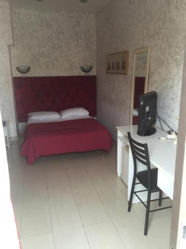 a bedroom with a red bed and a desk and a chair at Le Relais de Bamako in Bamako