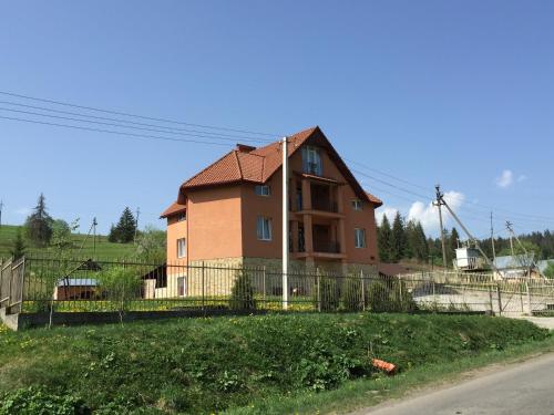 a house with a fence in front of a street at Pylypets Inn in Pilipets