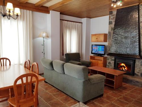 sala de estar con sofá, mesa y chimenea en Apartaments Cal Noi, en Camprodon