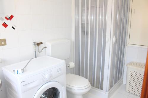 een witte badkamer met een wasmachine bij La Fata in Balestrate
