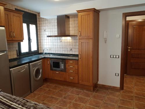 a kitchen with wooden cabinets and a washer and dryer at Apartaments Cal Noi in Camprodon
