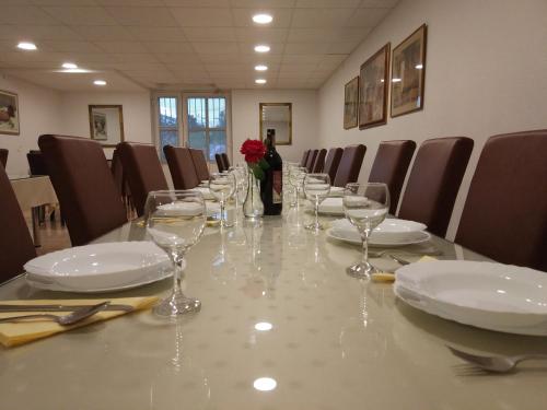 a long table with glasses and plates and a red rose at Guest House Regina Mundi in Međugorje