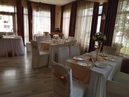 a dining room with white tables and white chairs at Mon Cheri in Drobeta-Turnu Severin