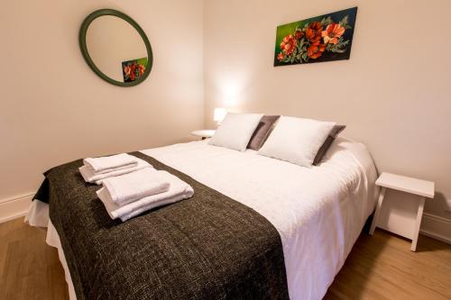 a bedroom with a bed with white sheets and a mirror at Casa do Tanque T2 in Arouca