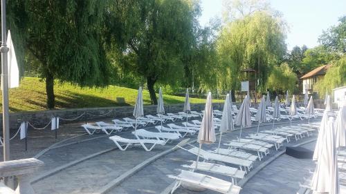 a row of white lounge chairs with umbrellas at Casa Allegra in Orta San Giulio