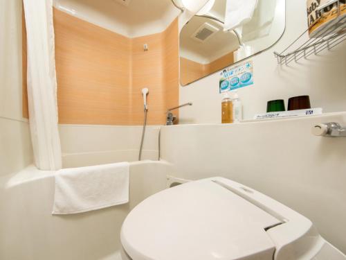 La salle de bains blanche est pourvue de toilettes et d'une baignoire. dans l'établissement Super Hotel Matsumoto Ekimae, à Matsumoto