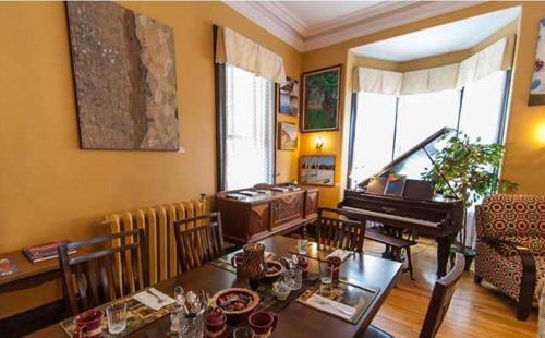 uma sala de estar com uma mesa e um piano em Carriage House Inn em Fredericton
