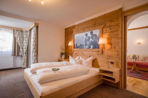 a bedroom with a large bed with a wooden wall at Hotel Viktoria & Landhaus Joggl in Mayrhofen