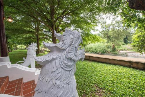 a statue of a person standing next to a fence at Phuttal Residence in Phra Nakhon Si Ayutthaya