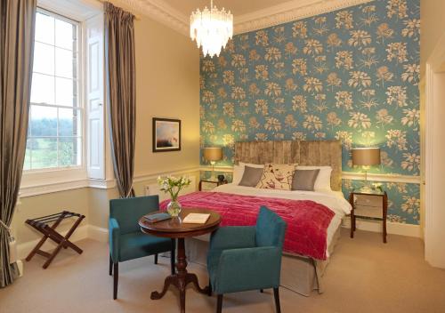 a bedroom with a bed and a table and chairs at Plas Nanteos Mansion in Aberystwyth