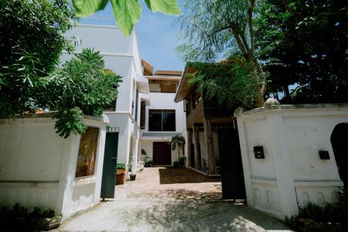 a white house with a fence and trees at Mammoth Art Studio Pool villa in old city in Chiang Mai