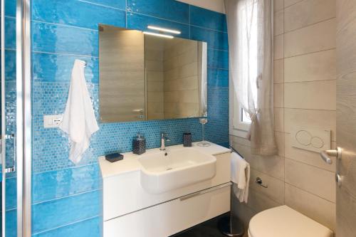 baño de azulejos azules con lavabo y aseo en B&B Da Peo en Porto San Giorgio