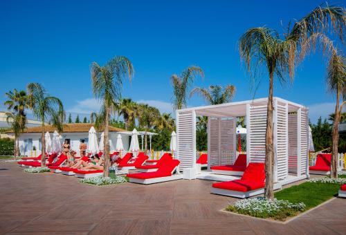Selectum Luxury Resort Belek في بيليك: مجموعة من الكراسي الحمراء والنخيل على الفناء
