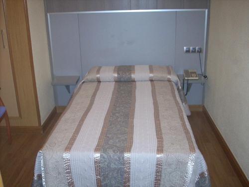 1 cama en una habitación pequeña con 2 mesas en Hotel Corona de Castilla, en Villares de la Reina