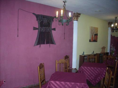 un comedor con una pared rosa con una cruz en la pared en Hotel Corona de Castilla, en Villares de la Reina