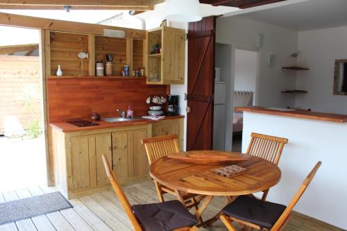 a kitchen with a wooden table and chairs at Résidence Bois Flotté in Sainte-Anne