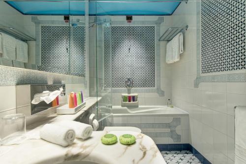 a white bathroom with a sink and a tub at Grand Hotel Royal in Sorrento