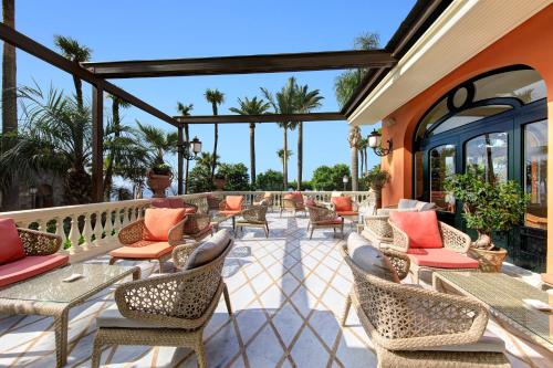 a patio with tables and chairs and palm trees at Grand Hotel Royal in Sorrento