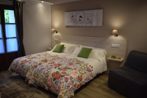 a bedroom with a large bed and a chair at L'Arbolea de Rodiles in Villaviciosa