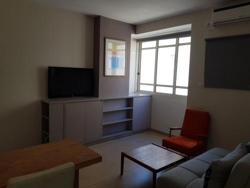 a living room with a tv and a couch and a table at HaYarkon Street Apartment in Tel Aviv