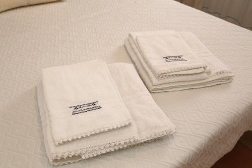 Tres toallas blancas están sentadas en una cama. en B&B Il Tramonto, en Castelsardo