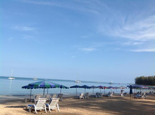a group of chairs and umbrellas on a beach at Ruan Mai Naiyang Beach Resort in Nai Yang Beach