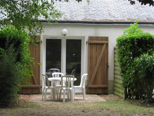 PloemelにあるLes Cottages Du Golf De Saint Laurentの家の前のパティオ(椅子、テーブル付)