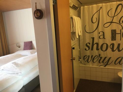 a room with a bed and a shower in it at Hotel Garni Rösslipost in Unteriberg